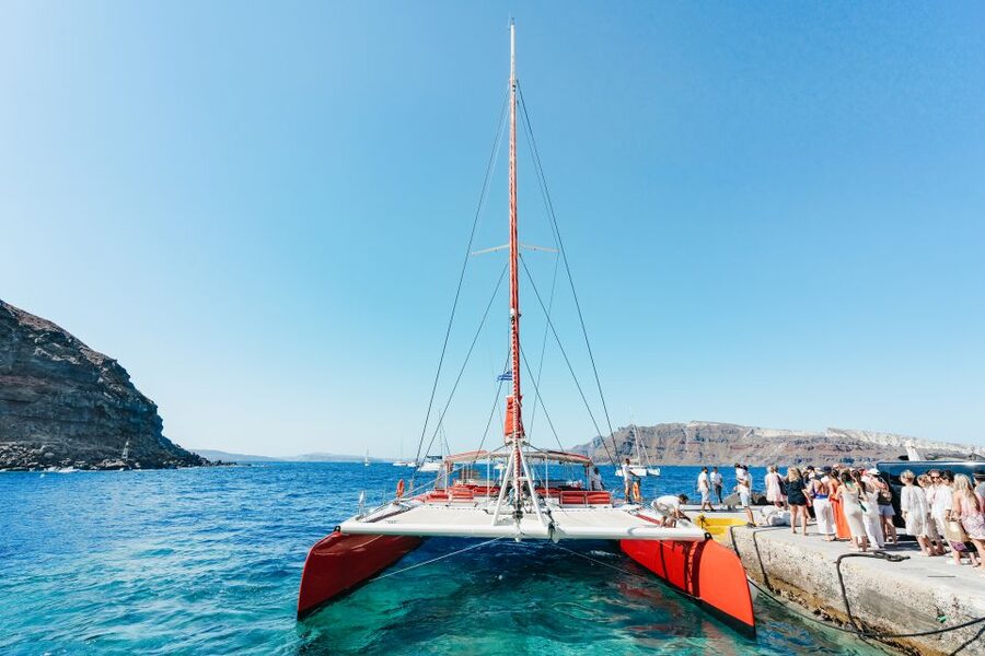 Santorini: Catamaran Tour with BBQ Dinner, Drinks, and Music - Boarding at Ammoudi Bay and settling into the catamaran